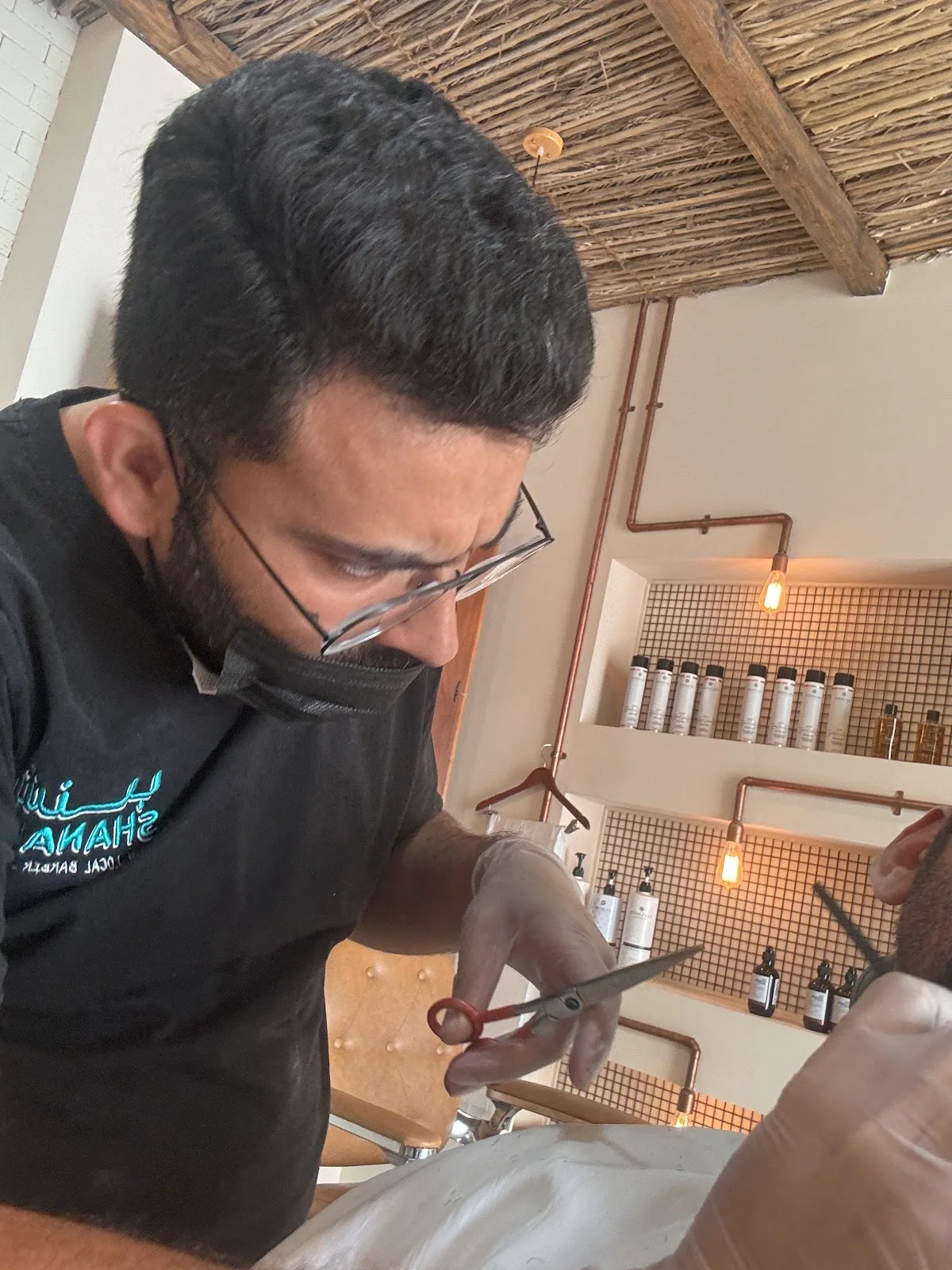 Barber in a Shanab shirt giving a precise scissor cut