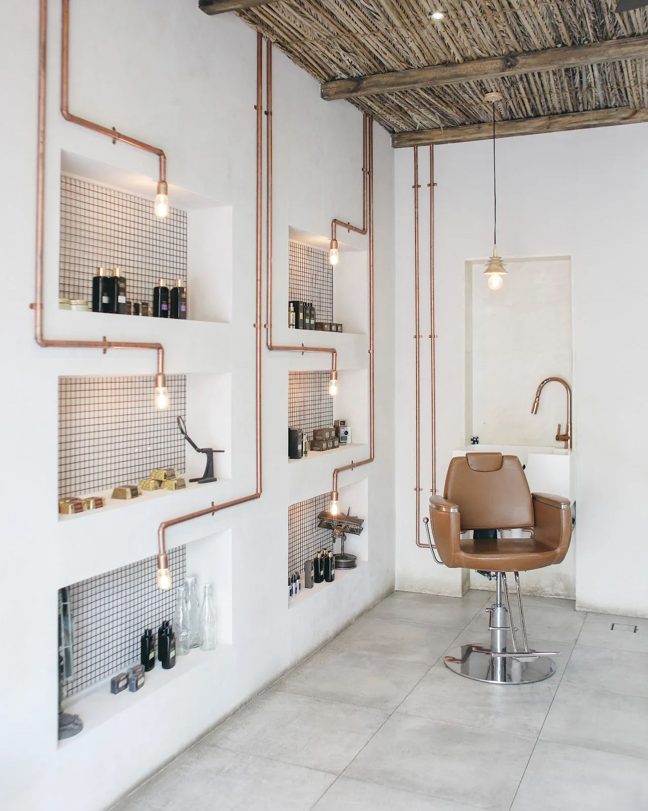 Barber station with product shelves backlit by warm bulbs and copper pipes