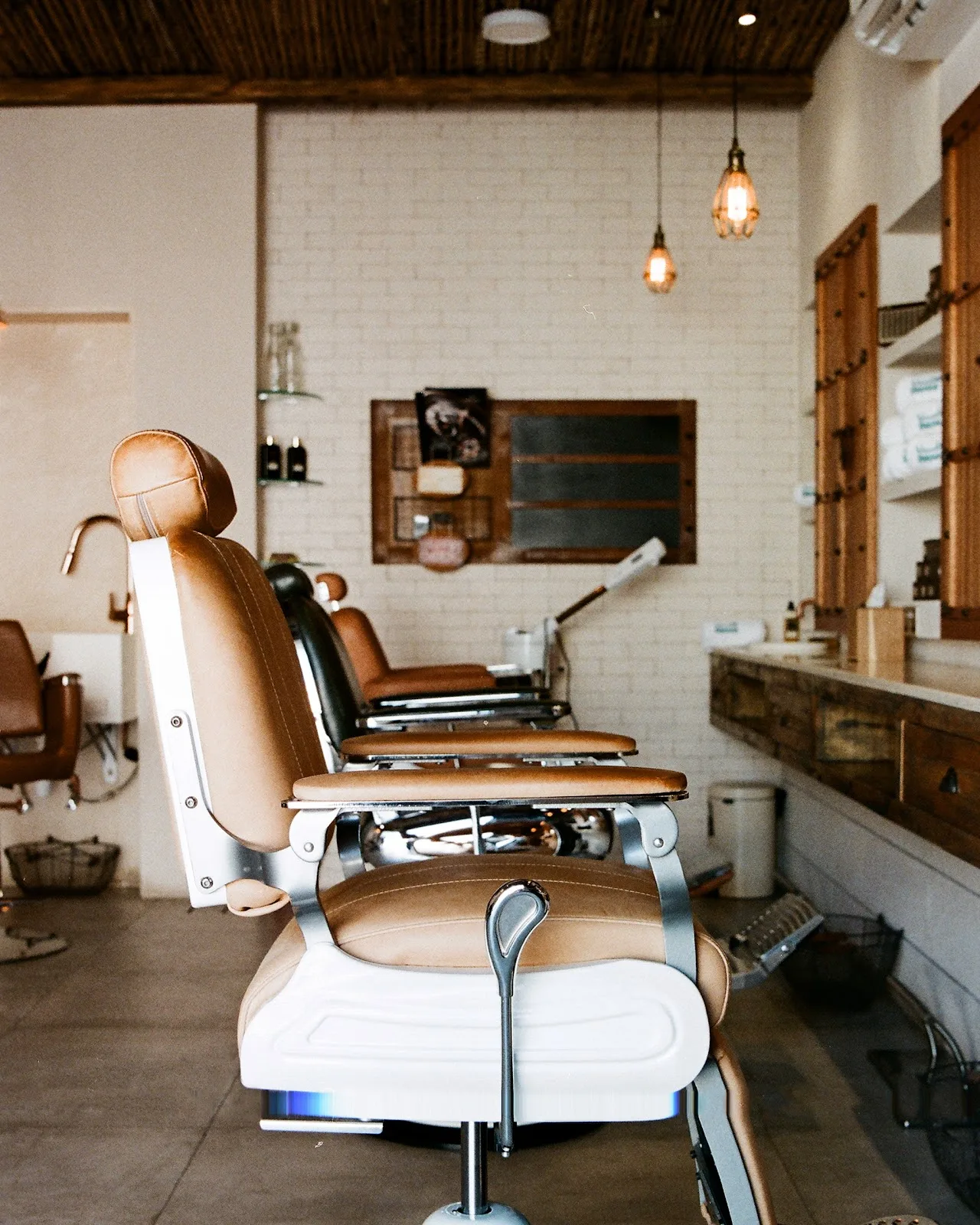 Row of tan-and-white barber chairs along a styling counter
