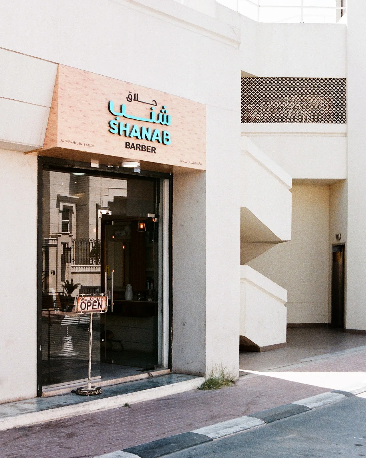 Shanab Barber glass entrance beside a pale building façade