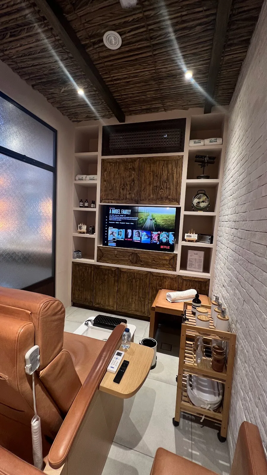Relaxation room with leather recliner, foot spa and a wall-mounted TV playing Netflix