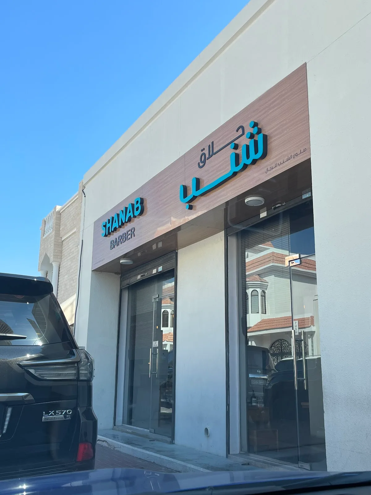 Shanab Barber shopfront with teal sign seen from the street
