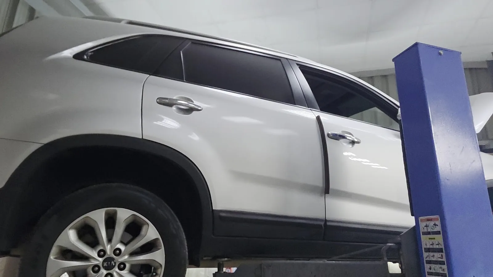 A white Kia SUV detailed and shining on the lift
