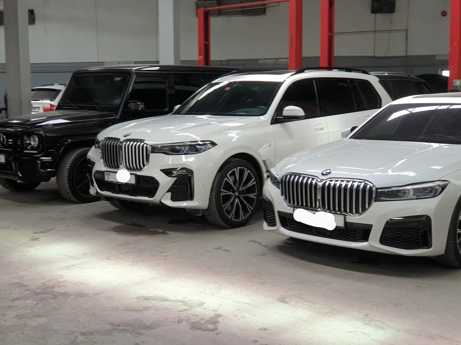 White BMW X7 and 7 Series parked in the workshop