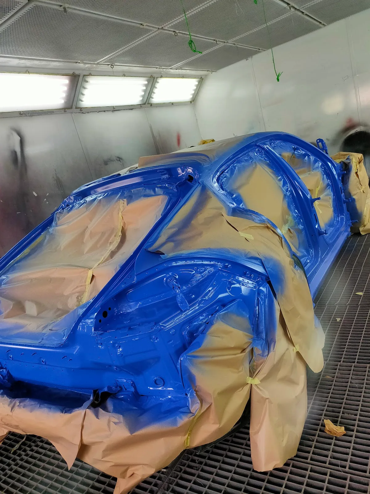 Car body in blue paint inside the spray booth