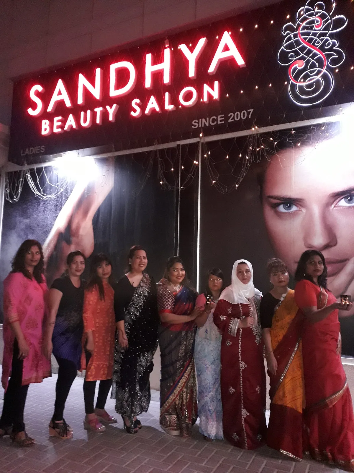The Sandhya Beauty Salon team gathered under the storefront sign