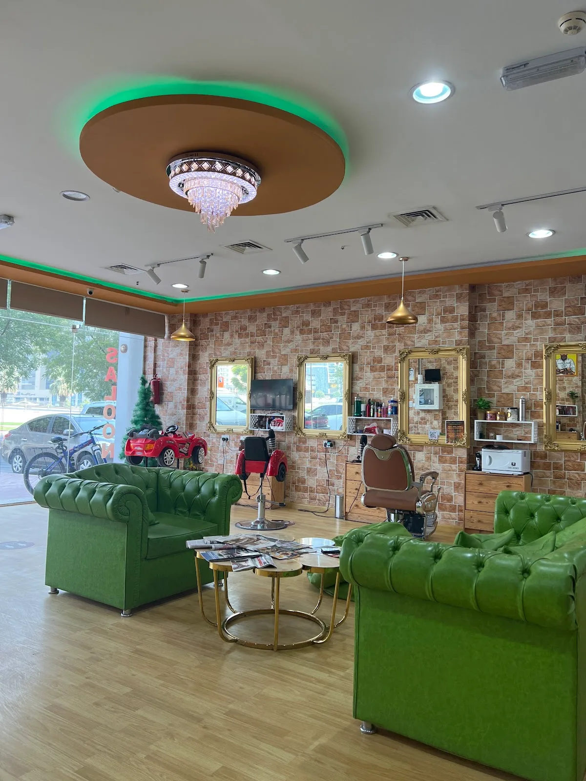 Green chesterfield lounge with gold-framed mirrors inside The BillionHairs Barber Shop