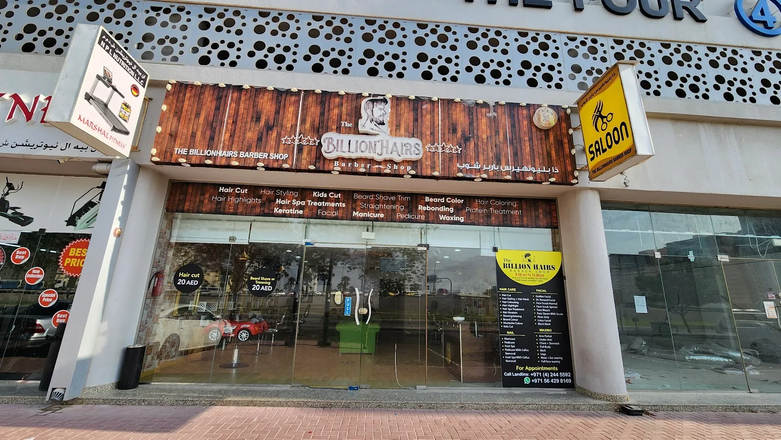 The BillionHairs Barber Shop storefront on Al Nahda with wood-panel signage and glass frontage