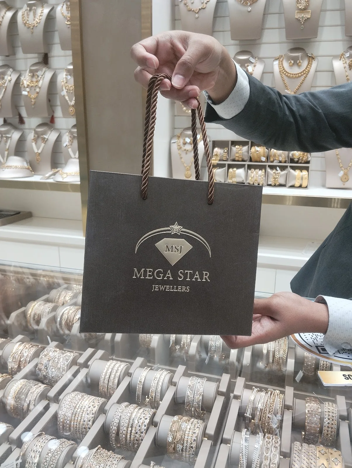 A Mega Star Jewellers branded shopping bag held in the showroom