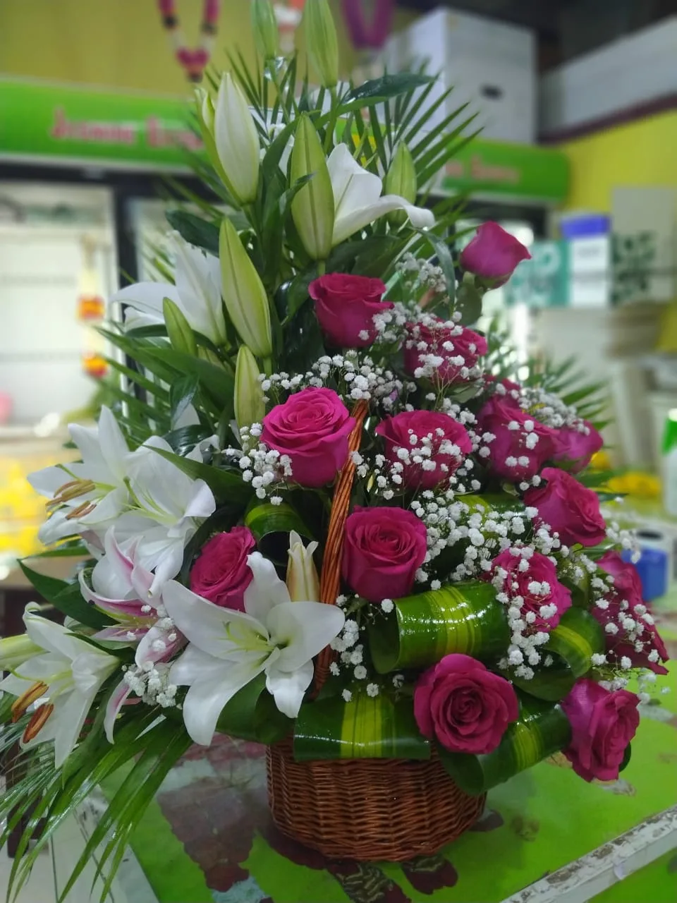 Basket arrangement of white lilies, magenta roses and baby's breath