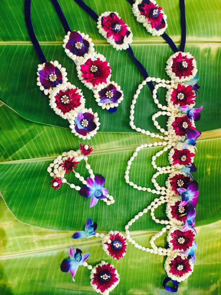 Purple and white floral jewellery set with orchids and jasmine arranged on a banana leaf