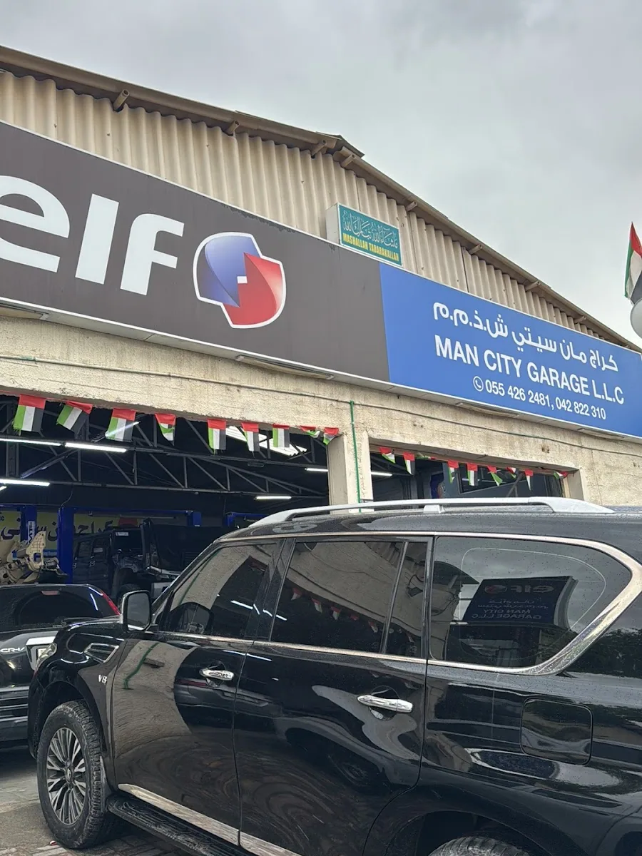 Man City Garage storefront with elf signage and a black SUV parked outside