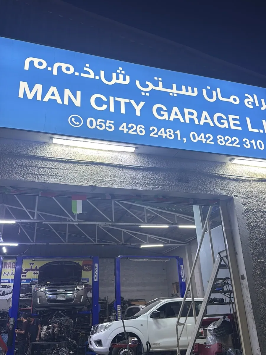 Man City Garage illuminated signboard above the open service bays at night in Umm Ramool, Dubai