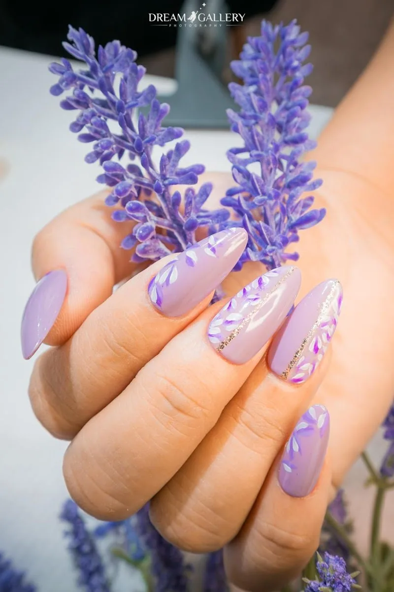 Lavender almond gel nails with hand-painted floral art and gold detailing
