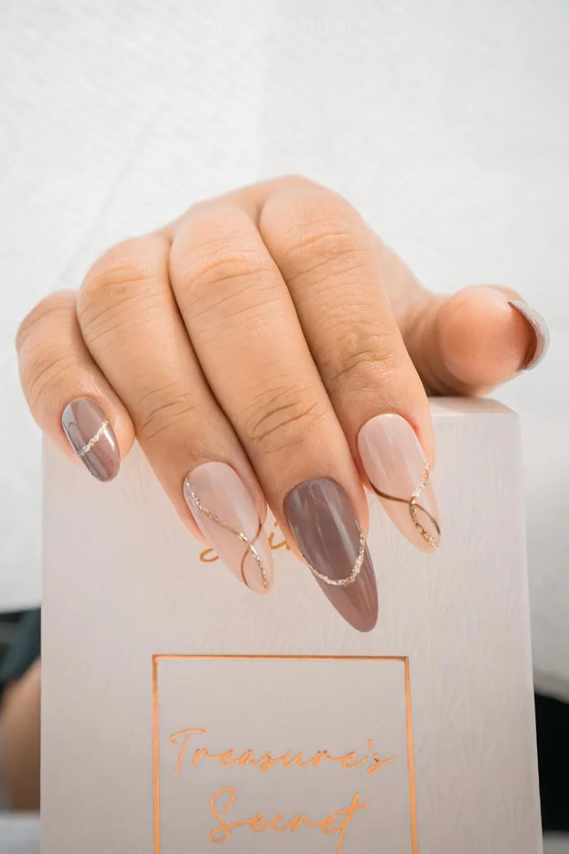 Nude and mocha almond nails with fine gold line work