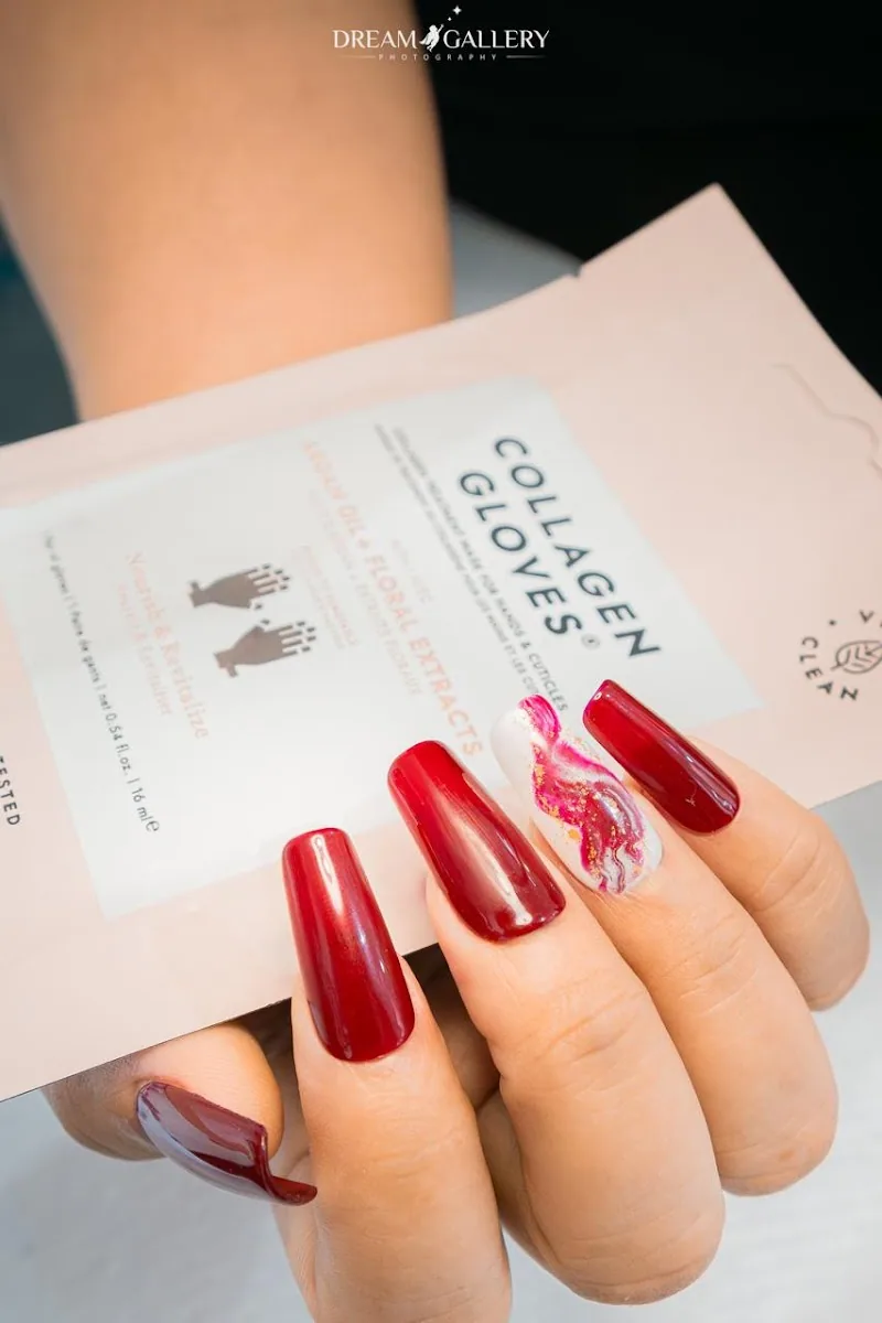 Deep red gel nails with a white and gold marble accent