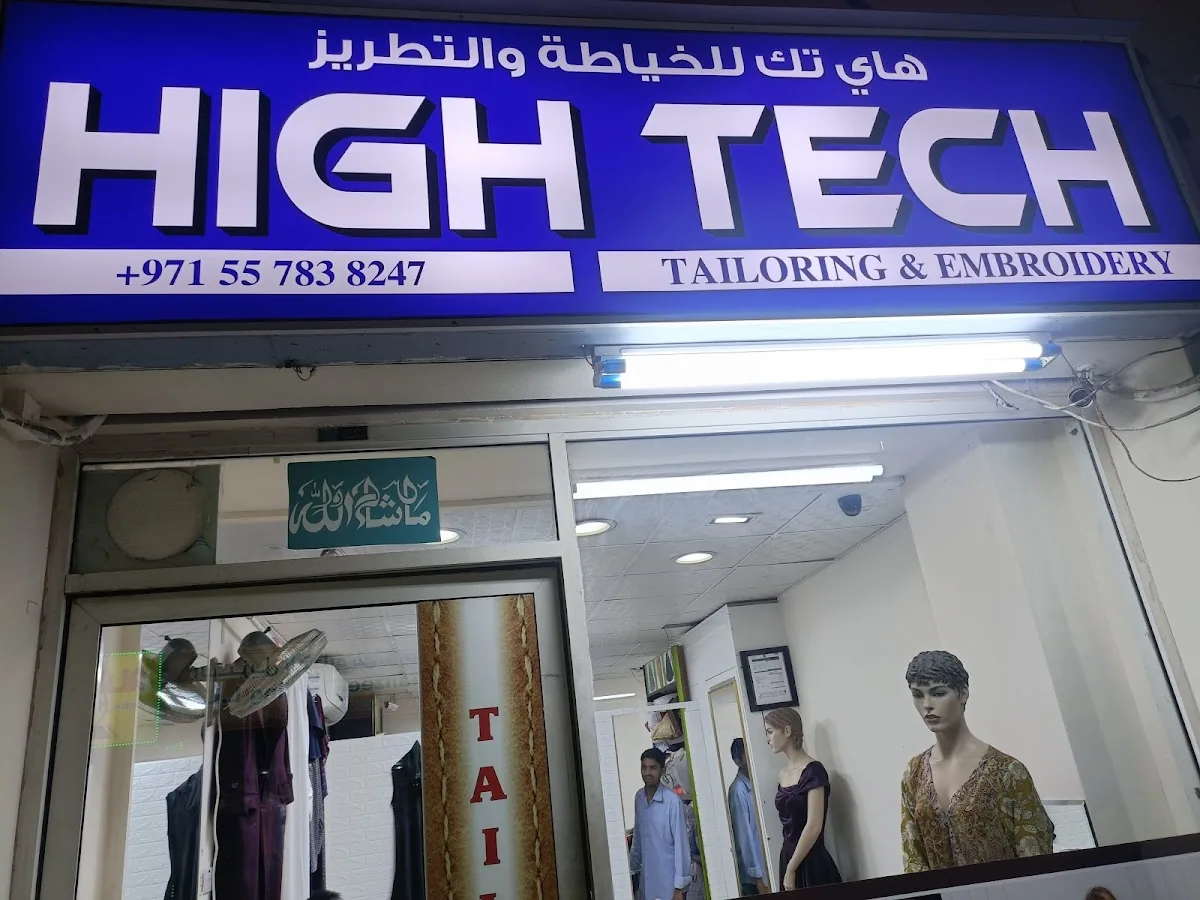 The illuminated HIGH TECH Tailoring & Embroidery shopfront sign at night in Al Satwa, Dubai