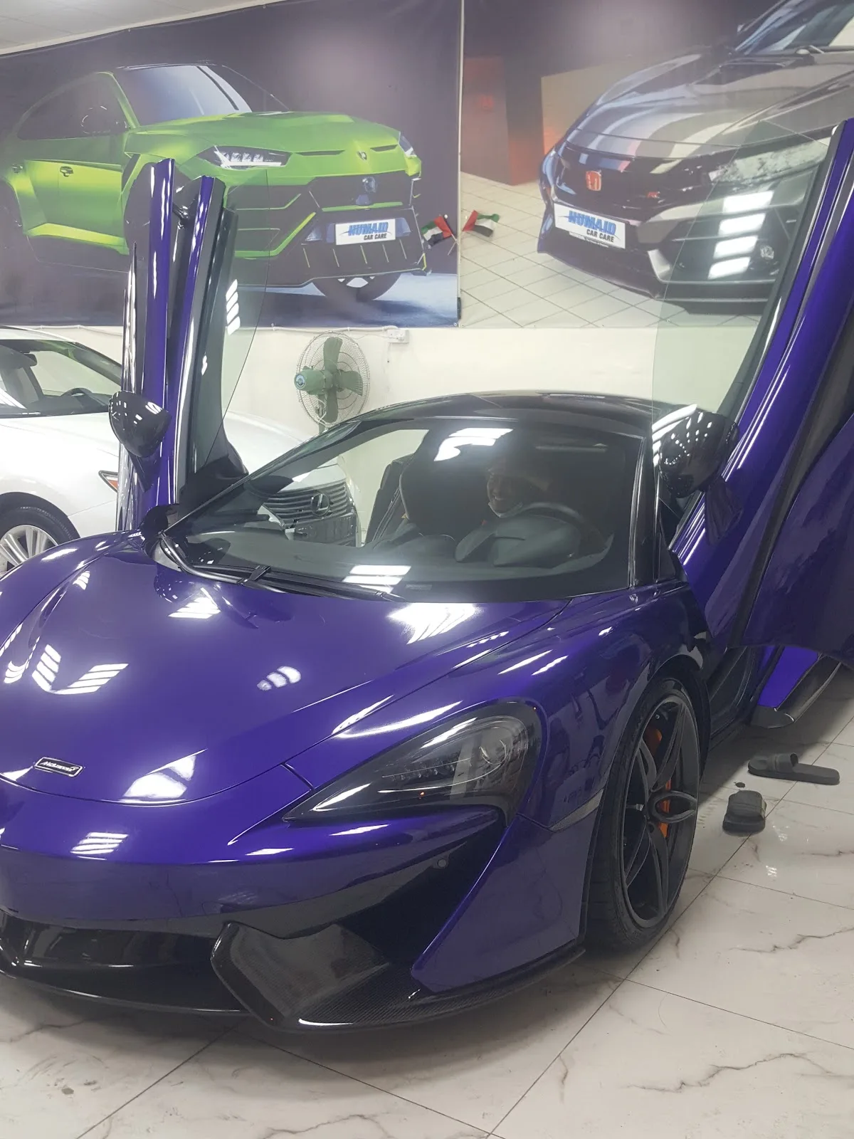 A purple McLaren with doors raised inside the workshop