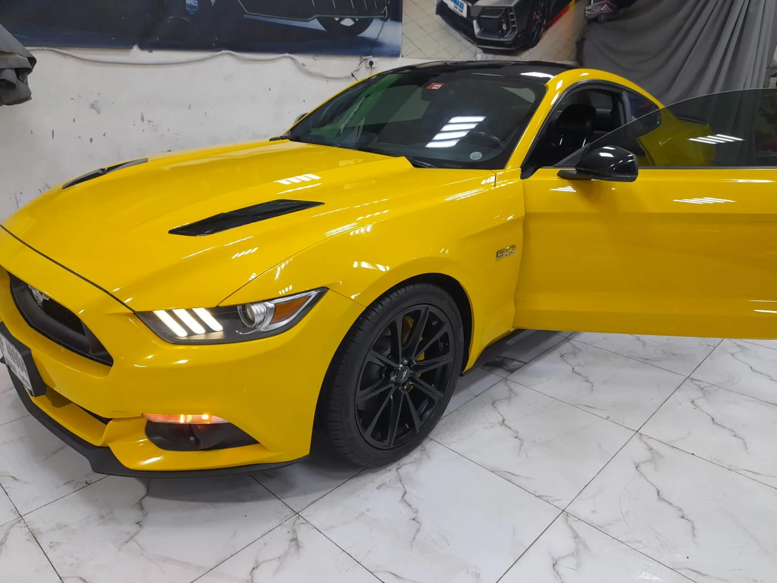 A yellow Ford Mustang GT on the workshop floor
