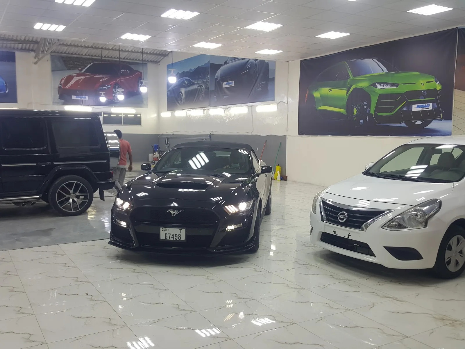 Detailed cars parked under supercar wall murals inside the HUMAID showroom