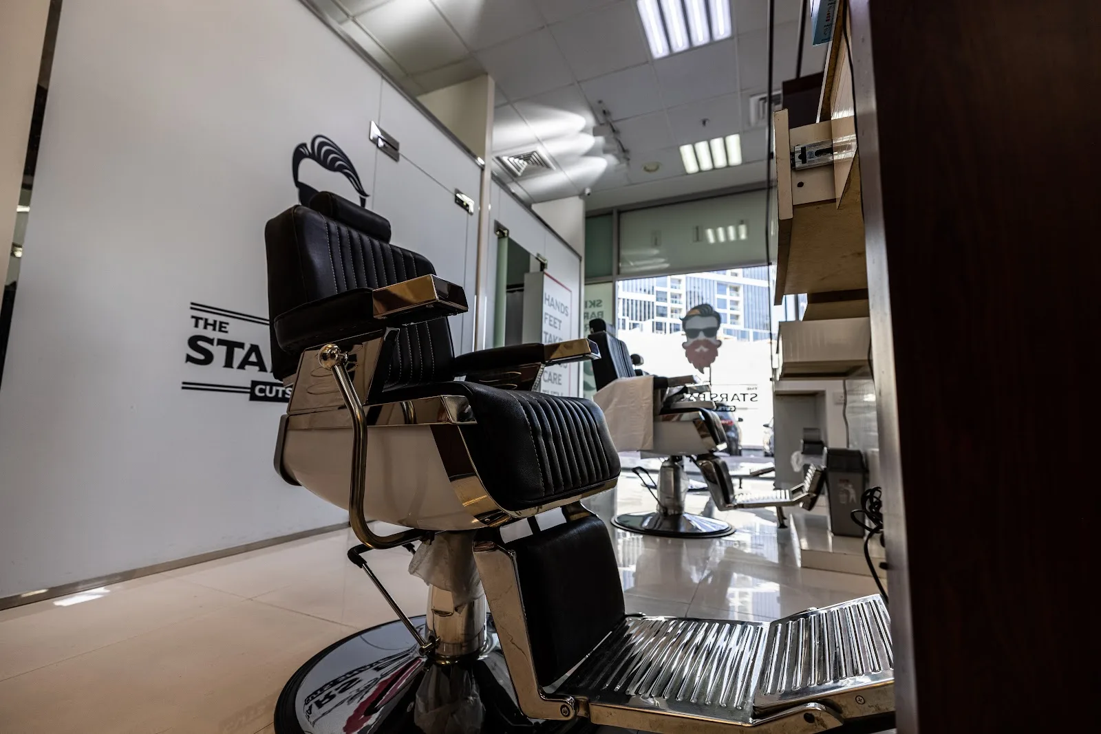 Polished black-and-gold barber chairs inside The Stars Barber, with the shop's logo on the wall