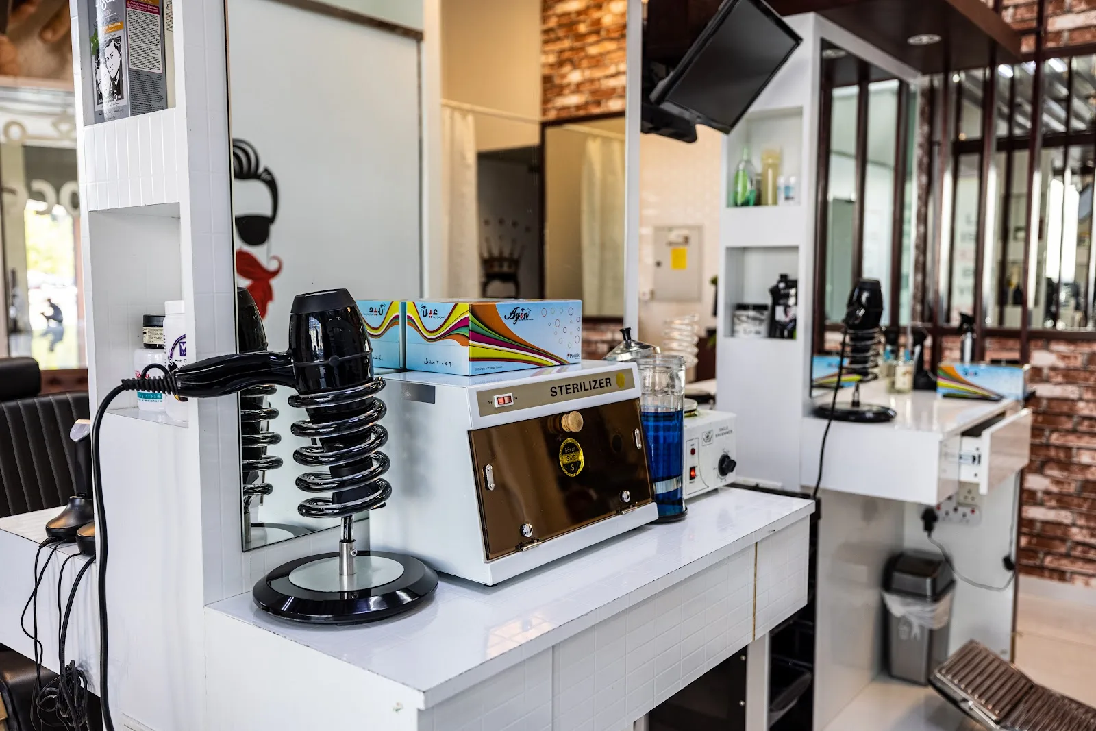 A barber station with a tool steriliser, dryer and mirrors at The Stars Barber