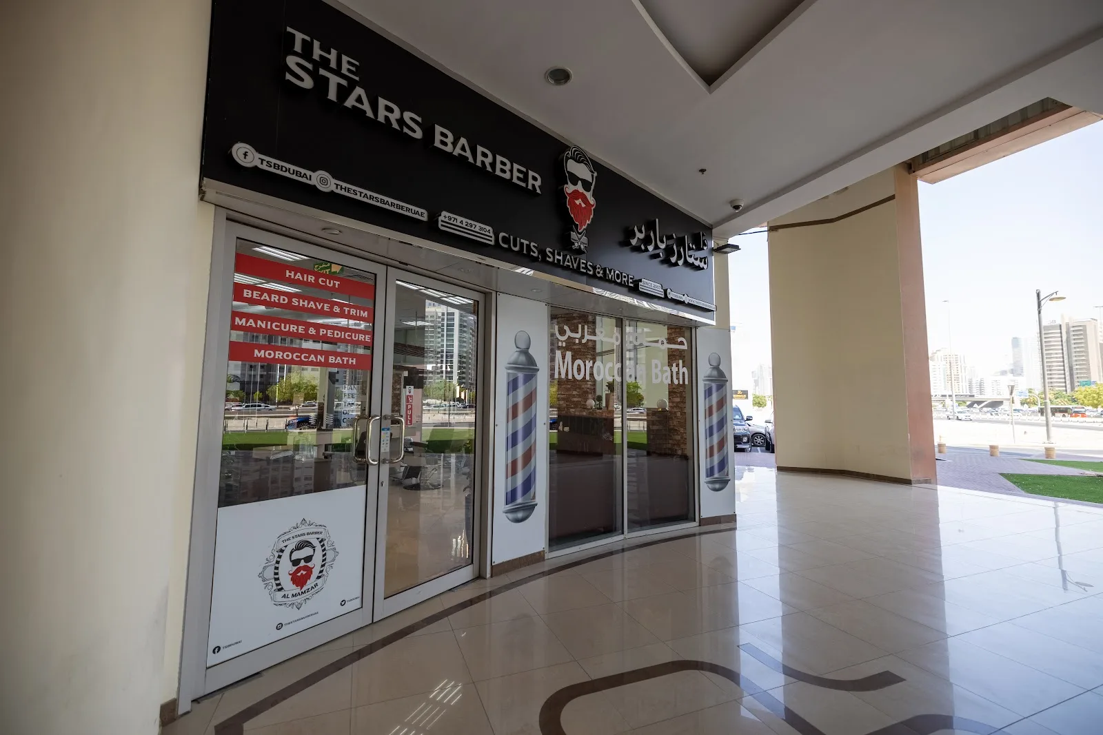 The Stars Barber storefront with barber poles and Cuts, Shaves & More signage in Al Mamzar