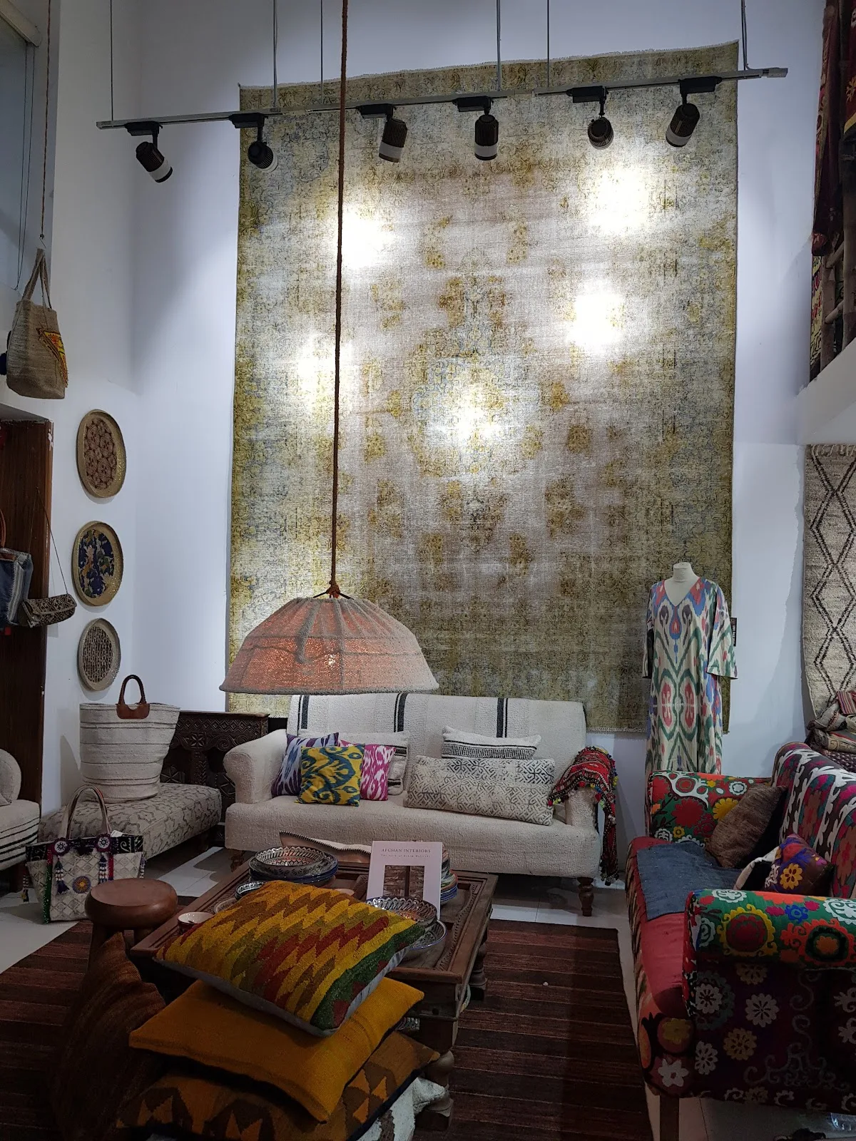 Styled showroom vignette with an overdyed rug, kilim cushions and a woven pendant light