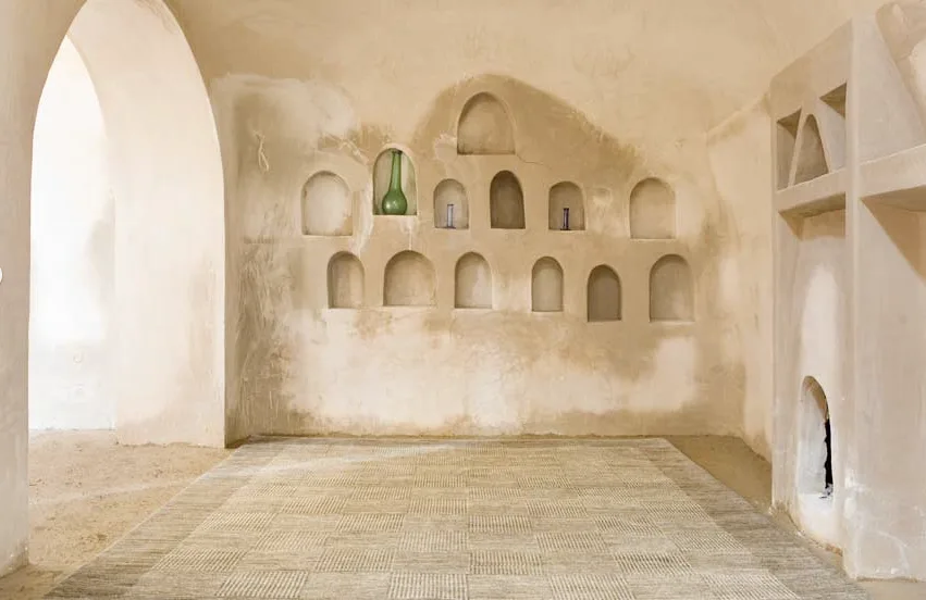 A natural flatweave rug in an arched mud-brick room