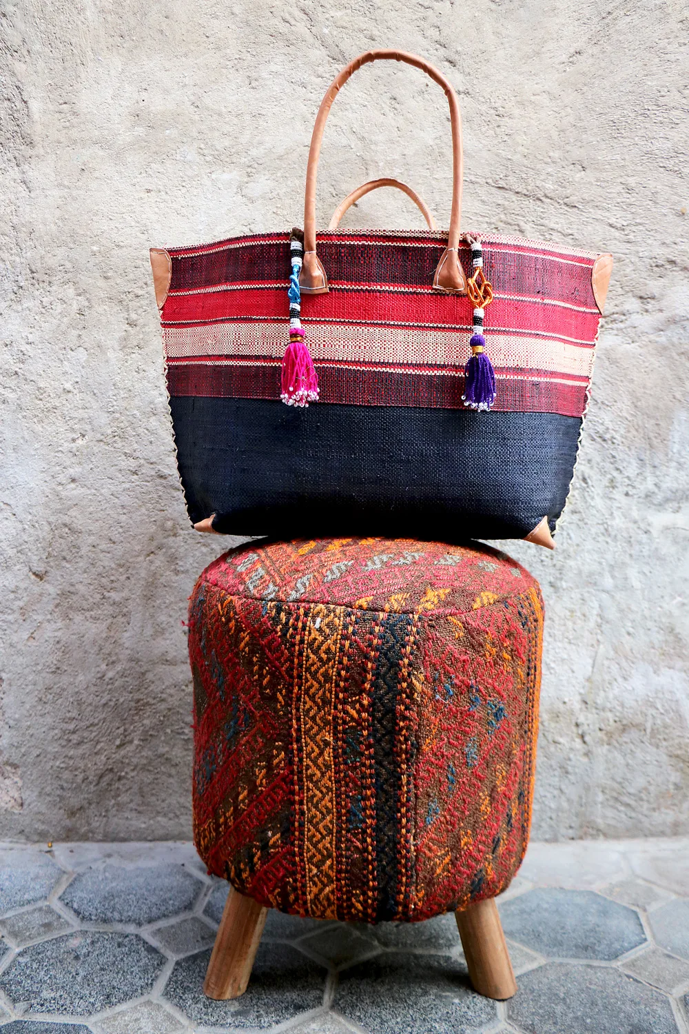 A striped market tote resting on a kilim-covered stool