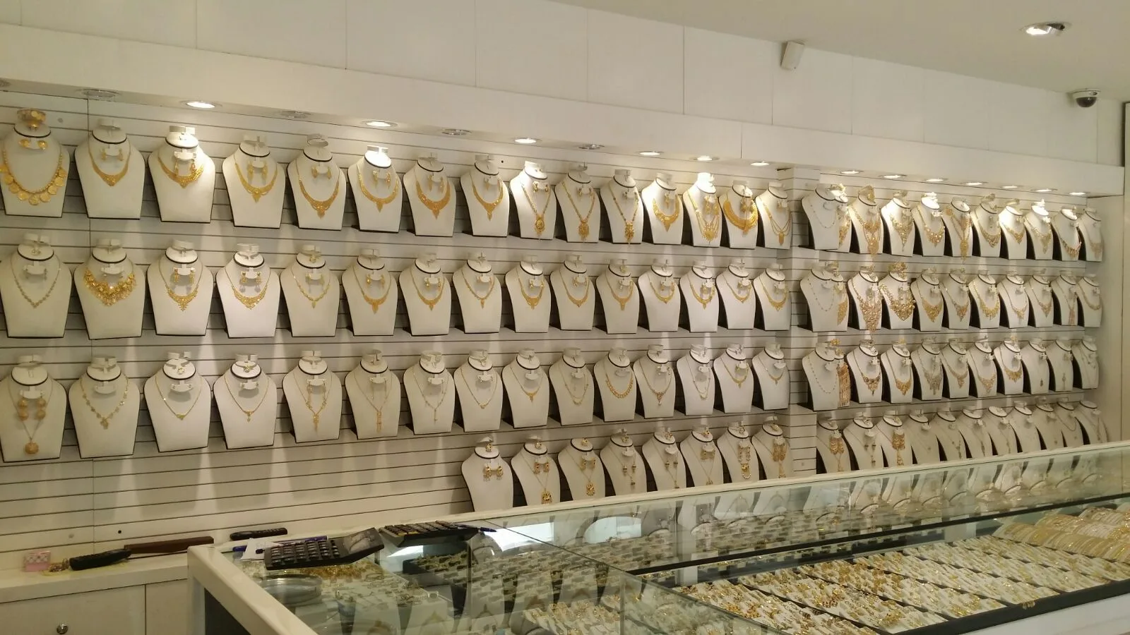 Display busts of gold necklaces above a long glass jewellery counter