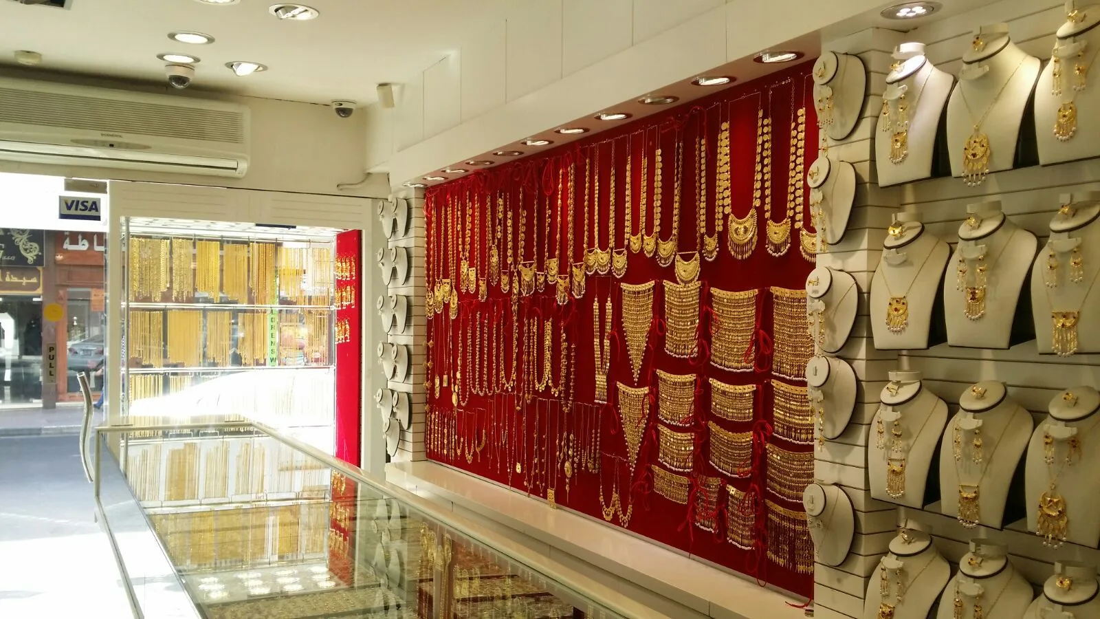 Gold necklaces and bridal sets on a deep-red velvet display wall inside Bu Yousif Jewellery, Al Satwa