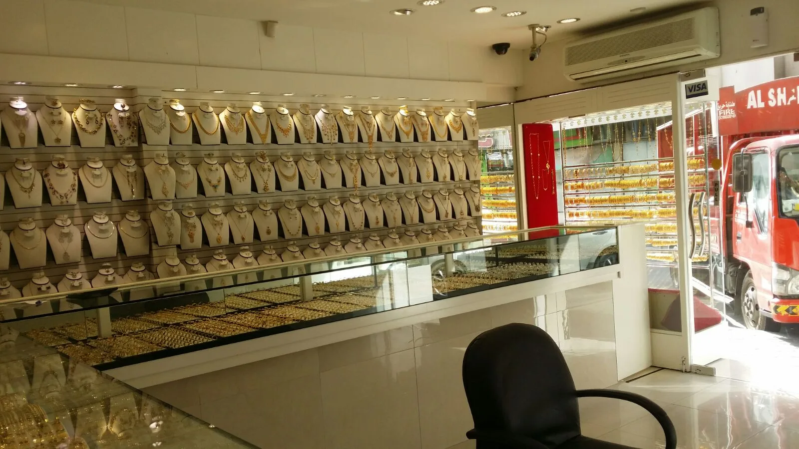 Interior view of lit display counters and gold necklace wall