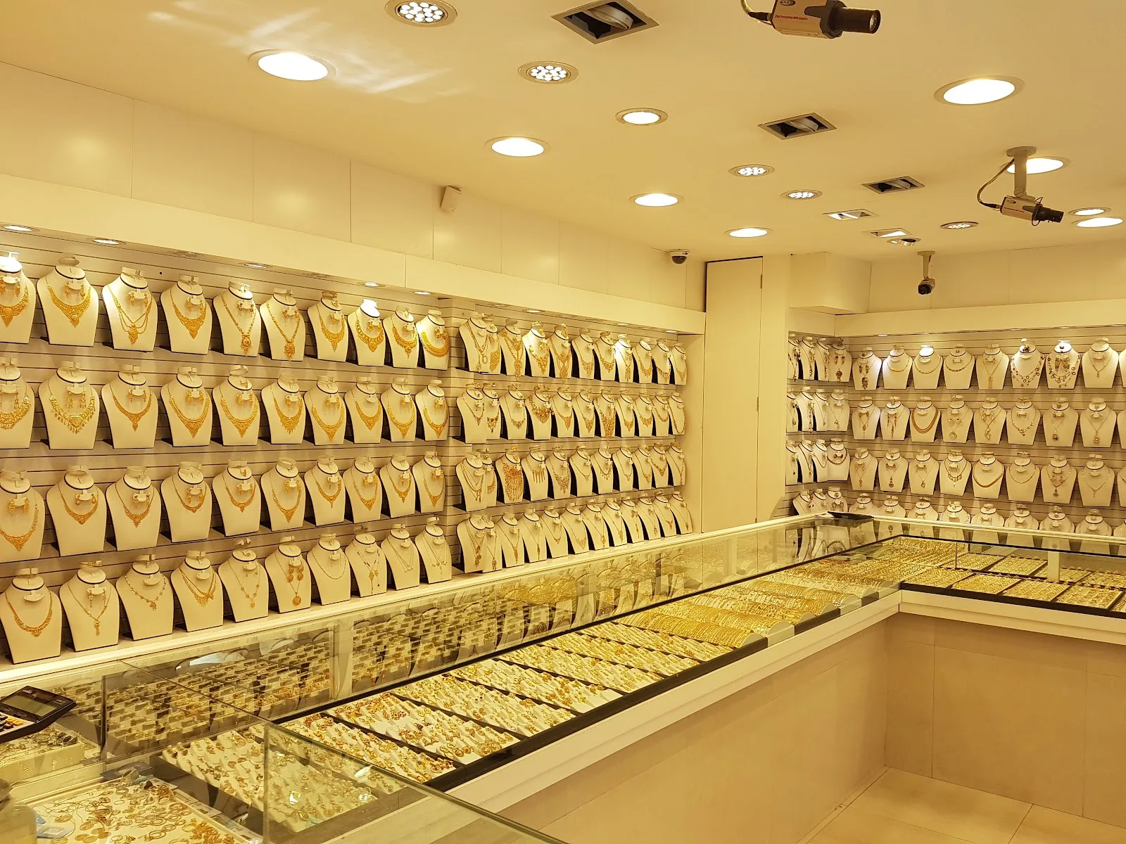 Wall of gold necklaces displayed on white busts inside the showroom
